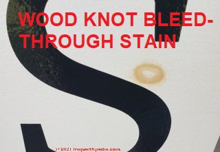 Tan oval stain on white painted surface of a sign is probably pine tar bleed-through invited by solvents in the paint (C)InspectApedia.com Anon