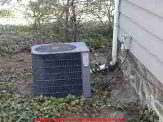Photograph of a typical residential air conditioning compressor condenser unit, an older model, with a few visible defects and concerns