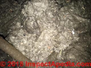 Mineral wool insuilation in an older installation may be darkened with soot and dust (C) InspectApedia.com