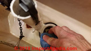 Cleaning the flush valve seat before installing a new toilet flapper valve (C) Daniel Friedman at InspectApedia.com