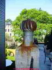 Rusty turbulator cap or turbine cap set atop a masonry chimney (C) Daniel Friedman