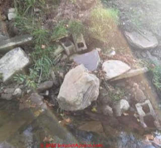 Broken concrete and bricks on creek bank (C) InspectApedia.com Ruth Adams
