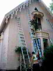 Photograph of a newly painted building exterior of an older home with small children present. Was lead paint left scattered on the ground in the play area?.