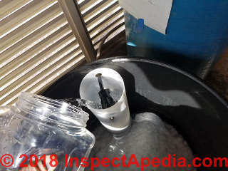Adding the proper amount of household bleach to the brine tank float well to begin water softener sanitize procedure (C) Daniel Friedman InspectApedia.com