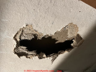 Hole punched in grayboard sheathing  - is this an asbestos hazard? (C) Inspectapedia.com John K