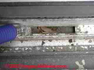 Metal slider window drain opening clog © D Friedman at InspectApedia.com 