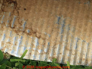 Yellow fibrous insulation bonded to underside of corrugated metal roofing: identification as probably fiberglass, possibly mineral wool, less-likely, wood fiberboard (C) InspectApedia.com  FreiseJ