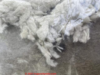 White fibrous insulation, probably fiberglass; also see mineral wool (C) InspectApedia.com Jordan