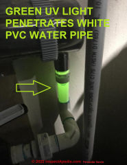 Green UV light penetrates white PVC water pipe - visible in semi-darkness (C) InspectApedia.com Garcia