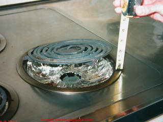 Electric range with aluminum foil on burner pan - DON'T DO THIS (C) InspectApedia.com