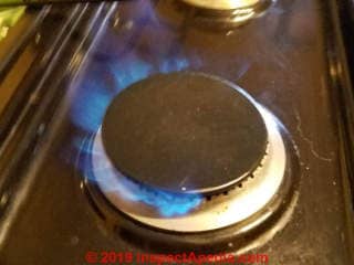 Gas burner cap is crooked on the burner base, causing failure of the gas igniter or a lopsided and dangerous flame (C) Daniel Friedman at InspectApedia.com