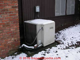 Heat pump with light snow cover in NY (C) Daniel Friedman at InspectApedia.com