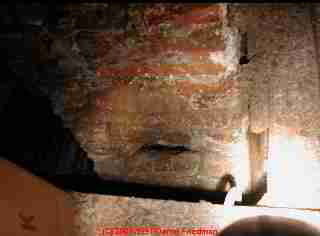 Photograph of a damaged unsafe brick chimney in an attic.