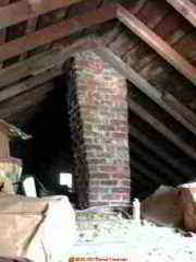 Photograph of a damaged unsafe brick chimney in an attic.