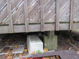 Deck pier inadequate: hollow block on dirt, no structural connections (C) InspectApedia.com Kahn, DovBer