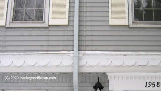 Ice on building exterior traced to gutter leak (C) InspectApedia.com and hankeyandbrown.com images used with permission