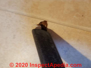 Vacuumin out dust from the damaged tile area (C) Daniel Friedman at InspectApedia.copm