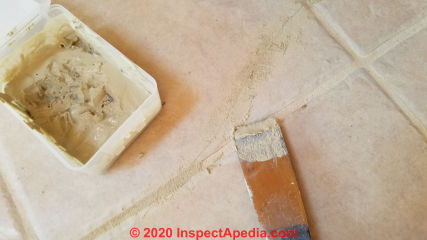 Cosmetic repair to minor cracks in ceramic tile by filling with color-matched grout (C) Daniel Friedman at InspectApedia.com