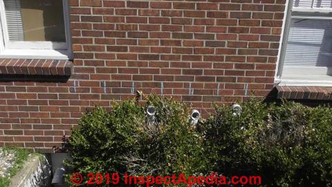 Navien CH water heater gas vents thorugh wall into bushes (C) InspectApedia.com Joe