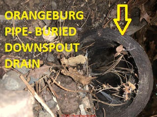 Black Orangeburg Pipe used as a downspout drain carrier (C) InspectApedia.com Rollings