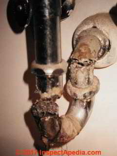 Chrome plated plumbing trap completely disintegrating from corrosion and leaking like mad (C) Daniel Friedman InspectApedia.com