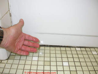 Sagging tile at shower pan means leaks are likely here, either from pan leaks or from leaks at a shower drain that has been damaged by movement (C) Daniel Friedman at InspectApedia.com