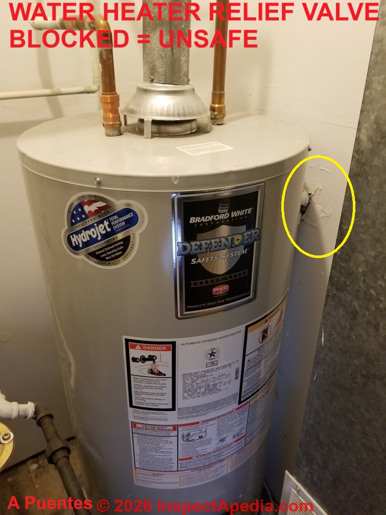 Unsafe, water heater relief valve is against wall, inaccessible, and worse, may not be able to open. (C) A Puentes InspectApedia.com