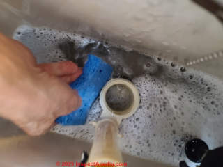 Step in removing an old toilet - use a sponge to get the last bit of water out of the flush tank (C) Daniel Friedman at InspectApedia.com