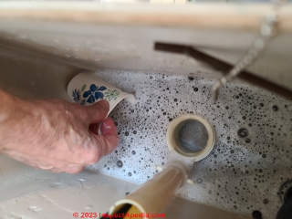 Step in removing an old toilet - use a cup to finish bailling out the flush tank (C) Daniel Friedman at InspectApedia.com