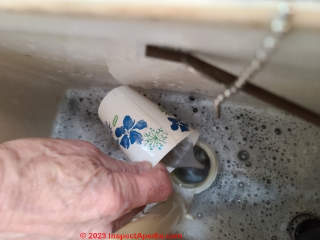 Removing an old toilet - use a cup to finish bailling out the flush tank (C) Daniel Friedman at InspectApedia.com  
