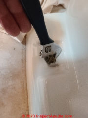 An adjusteable wrench can also remove toilet base mounting cap nuts (C) Daniel Friedman at InspectApedia.com