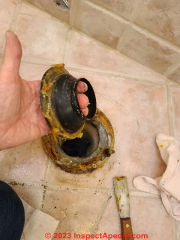 Remove the old wax ring seal remains before installing a new toilet  (C) Daniel Friedman at InspectApedia.com