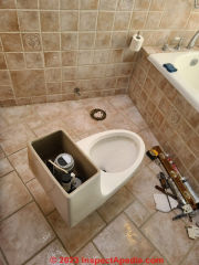 New toilet brought into the bathroom to prepare for its installation (C) Daniel Friedman at InspectApedia.com