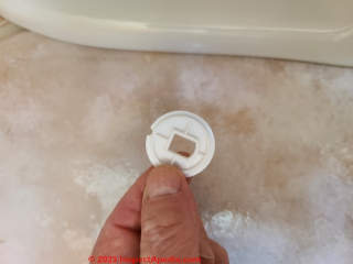 This plastic washer lets the plastic dome cap snap into place, covering the toilet mounting bolt cap nut (C) Daniel Friedman at InspectApedia.com