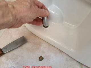 Hand tighten the toilet mounting bolt nut - not too tight or you may break the toilet (C) Daniel Friedman at InspectApedia.com