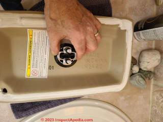 Install the dual flush valve into the toilet tank top (C) Daniel Friedman at InspectApedia.com