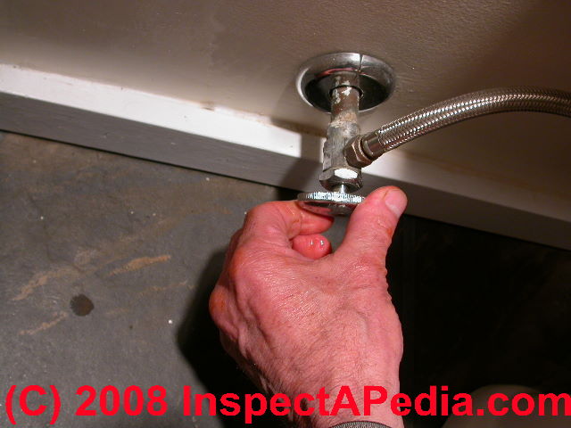 Unscrewing the lock nut that holds a toilet flush lever in place (C) Daniel Friedman at InspectApedia.com