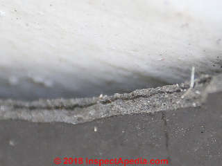 Edge of a broken synthentic roofing slate shows that it is not a layered material and it may contain reinforcing fibres (C) InspectApedia.com op cit