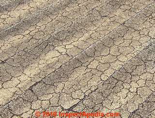 Cracked worn out roll roofing installed over a metal roof (C) InspectApedia.com