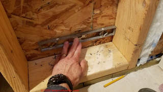 Using a small level to extend our cut line height from the mark on the wall stud onto the rear wall where the cut will be made   - (C) Daniel Friedman at InspectApedia.com