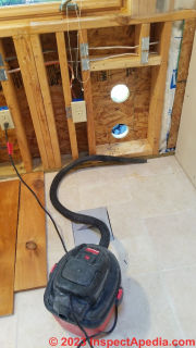 Vacuuming up sawdust helps assure good sealant and insulation installation later  - (C) Daniel Friedman at InspectApedia.com