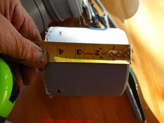 Measuring to cut a close nipple of 4-inch plastic to add the 45 degree angle elbow to a Cinderella toilet vent  - (C) Daniel Friedman at InspectApedia.com