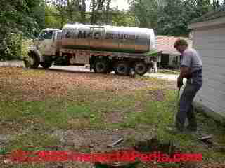 Photo of septic tank sludge and scum layer being broken up prior to septic tank cleanout © D Friedman at InspectApedia.com 