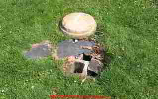 PHOTO of an unsafe septic tank cover placed over collpasing concrete blocks