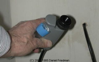 Photograph: using a borescope to examine a building wall cavity