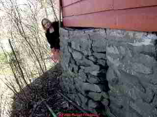 Photograph of a bulged, cracked, leaning stone foundation wall.