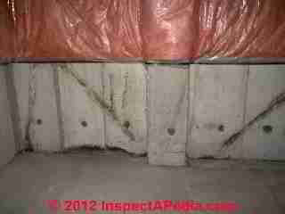 Photograph of contraditory diagonal "cracks" in a poured concrete foundation wall (C) InspectAPedia & C.C. 