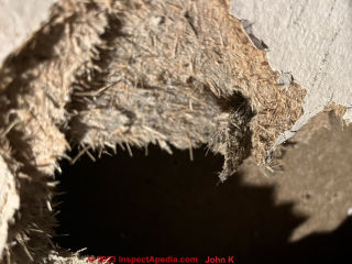 Hole punched in grayboard sheathing  - is this an asbestos hazard? (C) Inspectapedia.com John K