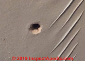 Hole in interior wall made by termite control company (C) InspectApedia.com WW