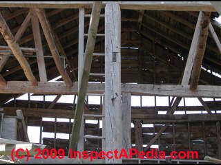 Checking cracks in the post of a post and beam barn in Northeastern U.S. and more than 100 years old (C) Daniel Friedman at InspectApedia.com